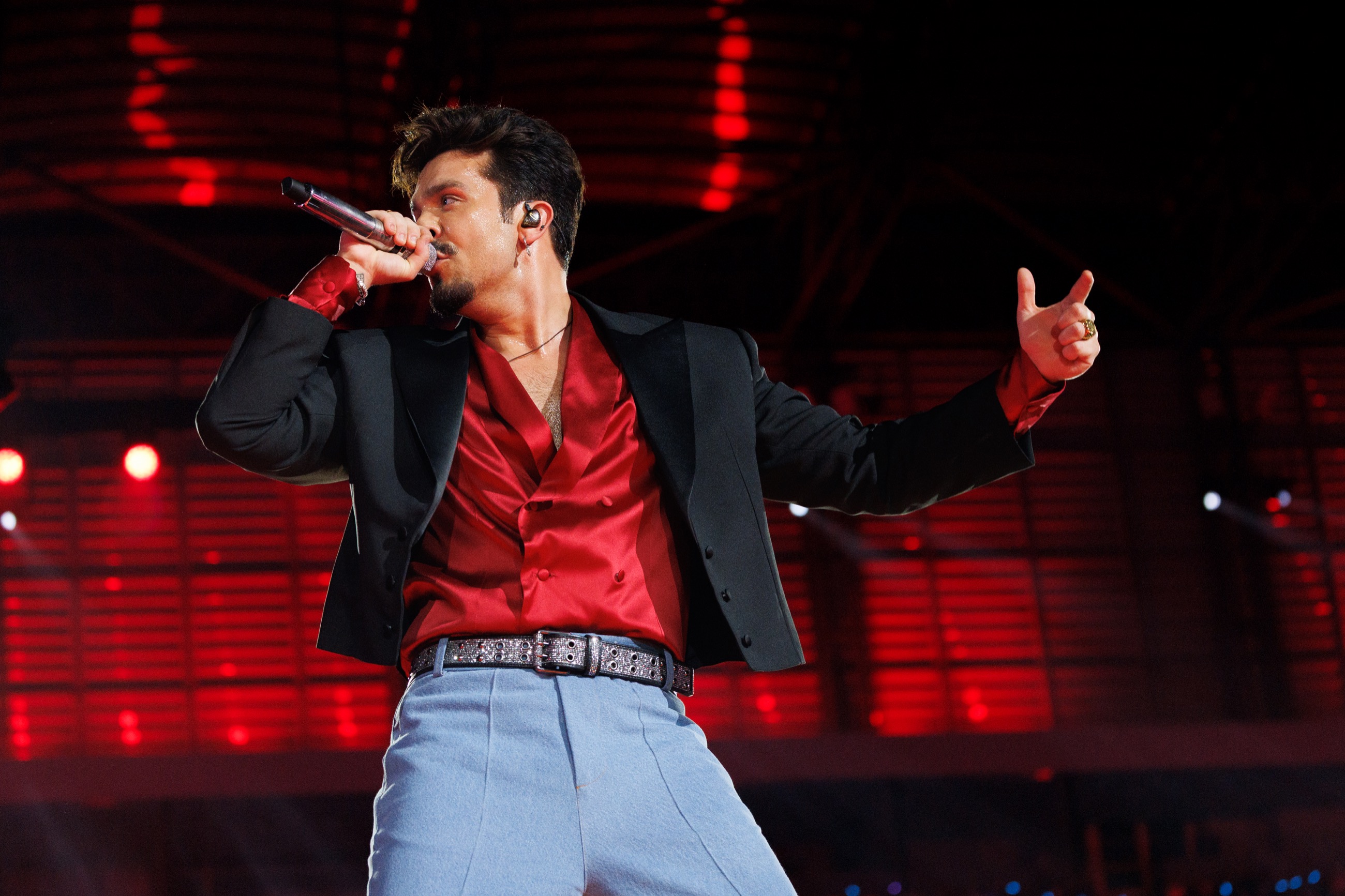 Luan Santana cantando com camisa vermelha e blazer preto